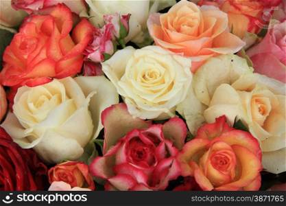 Roses in various shades of red, orange and pink in a bridal bouquet