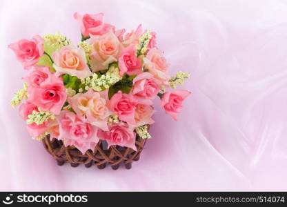 Roses in wood basket on fabric pink background