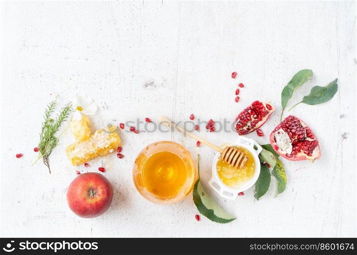 rosh hashana holiday - honey with apple and pomergranate over white desk background. border with copy space. rosh hashana holiday