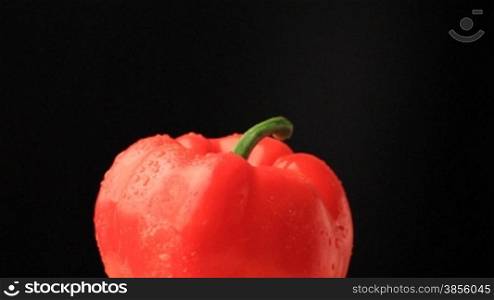 Rotation of red pepper. Under drops and on black background.
