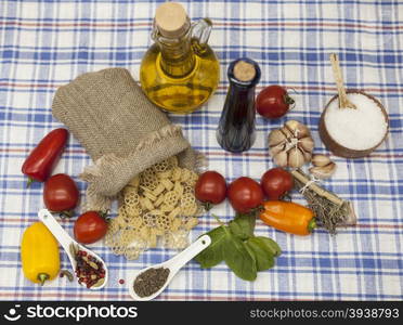 Rotelle Italian pasta set for the creation : cherry tomatoes, olive oil, balsamic sauce, garlic, spices, sea salt, salad on a rustic table.