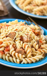 Rotini pasta with tuna and tomato sauce and grated cheese on top, photographed with natural light (Selective Focus, Focus in the middle of the first dish)