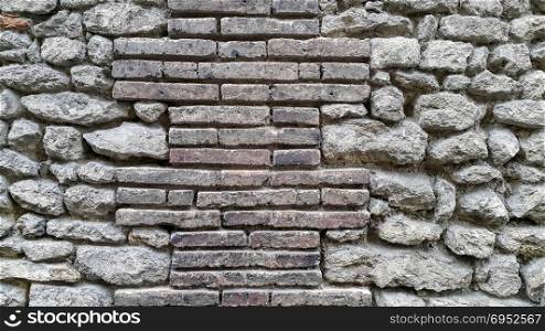 Rough ancient wall with bricks and cobblestones, close-up background