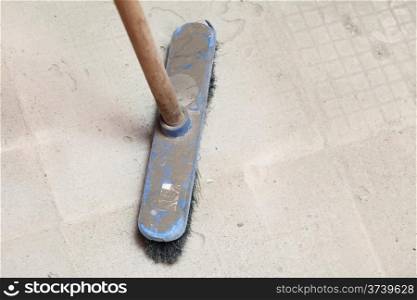 rough concrete at a job site using a large blue broom