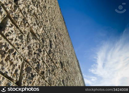 Rough textured brick wall looking up to a bright blue sky