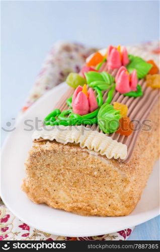 Roulade cake, decorated with colourful buttercream flowers. Yule Log Cake over light blue background. Selective focus
