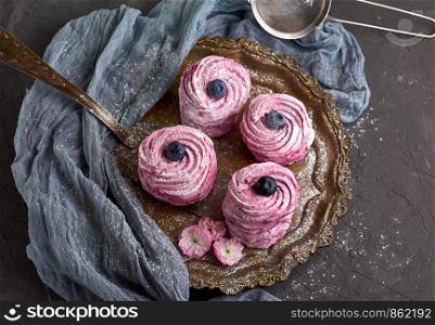round airy pink marshmallow with blueberries on an iron plate, top view
