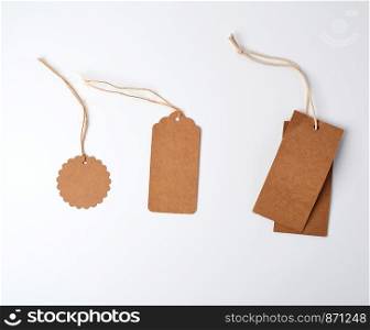 round and rectangular brown paper price tags hanging on a rope, white background