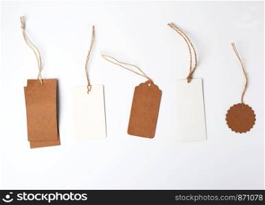 round and rectangular price tags from brown and white paper hang on a rope, white background