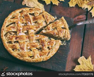 round apple pie on a brown wooden board, puff pastry, top view