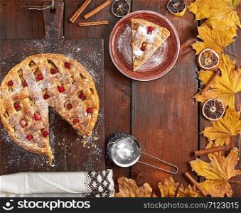 round apple pie on a rectangular old brown cutting board sprinkled with powdered sugar, top view