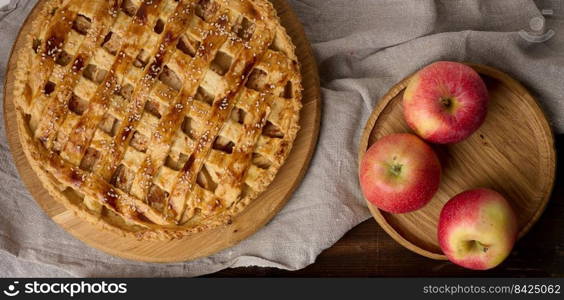 Round baked apple pie on a brown wooden table, top view