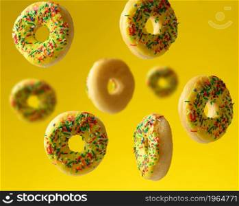 round baked donuts sprinkled with multicolored sugar sprinkle levitate on a yellow background