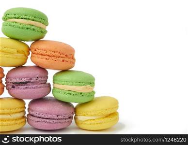 round baked multi-colored almond flour cakes macarons, dessert is laid in a stack in the shape of a triangle and isolated on a white background