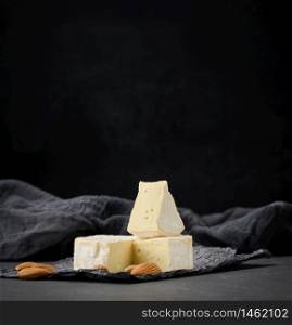 round brie cheese on black crumpled paper, wooden table