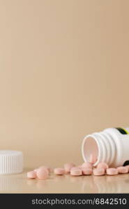 Round brown pills and white plastic bottle. Round brown pills and white plastic bottle on beige background
