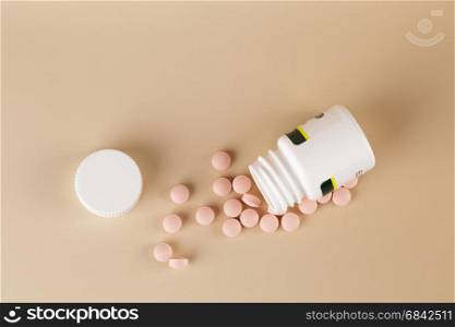 Round brown pills and white plastic bottle. Round brown pills and white plastic bottle on beige background