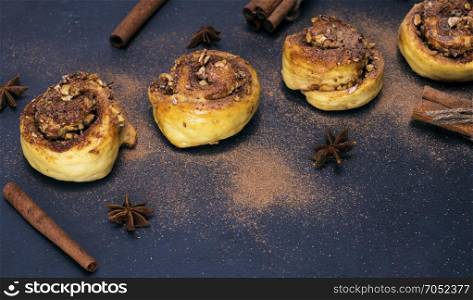 round buns with cinnamon in a row on a black background, top view