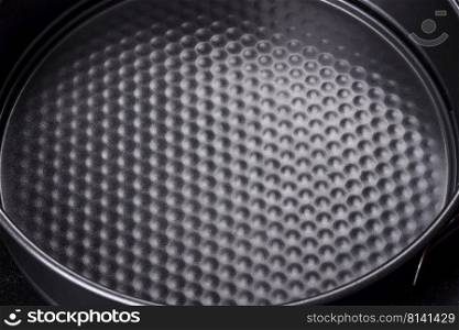 Round cake pan, tray or mould on a black concrete background. Cooking at home. Round cake pan, tray or mould on a black concrete background