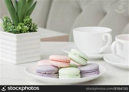 Round cookies on a plate and two cups on a table with flowers. cake in a plate and a cup on the table