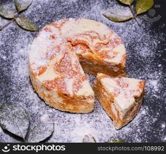 round dessert cheesecake with pumpkin on black background, top view
