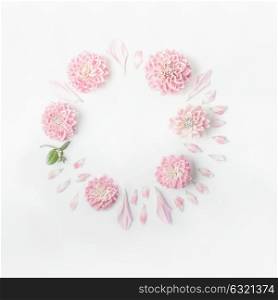 Round frame of pastel pink flowers and petals on white desk background. Floral wreath. Layout for holidays greeting of Mothers day, birthday, wedding or happy event