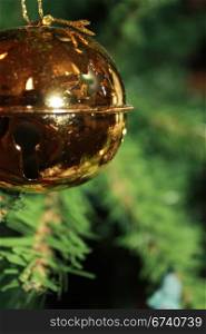 Round gold ornament hanging on a Christmas tree