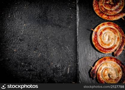 Round grilled sausages on a black background. High quality photo. Round grilled sausages on a black background.