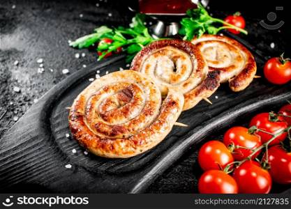 Round grilled sausages on a tray with tomato sauce. On a black background. High quality photo. Round grilled sausages on a tray with tomato sauce.