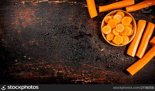 Round pieces of fresh carrots on a wooden plate. Against a dark background. High quality photo. Round pieces of fresh carrots on a wooden plate.
