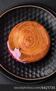 Round puff pastry croissant with raspberry filling or new york roll on dark concrete background