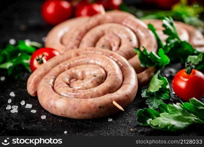Round raw sausages with tomatoes and parsley. On a black background. High quality photo. Round raw sausages with tomatoes and parsley.