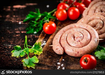 Round raw sausages with tomatoes and parsley. On a rustic background. High quality photo. Round raw sausages with tomatoes and parsley.