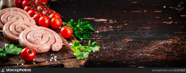 Round raw sausages with tomatoes and parsley. On a rustic background. High quality photo. Round raw sausages with tomatoes and parsley.