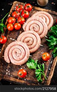 Round raw sausages with tomatoes and parsley. On a rustic background. High quality photo. Round raw sausages with tomatoes and parsley.