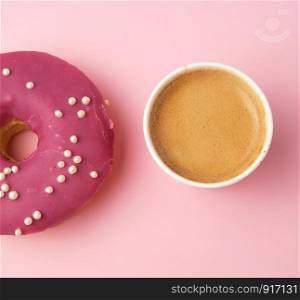 round red glazed donut and paper cup with coffee on a pink background, top view