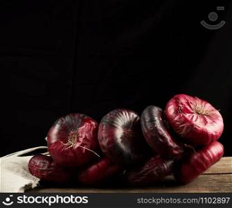 round red onion in husk on a gray linen napkin, black background, close up