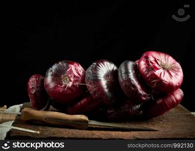 round red onion in husk on a gray linen napkin, black background, close up
