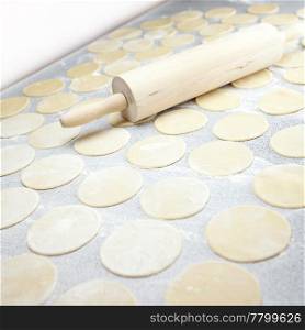 round shape of the dough and rolling pin with flour on the table