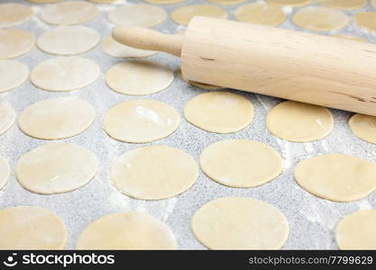 round shape of the dough and rolling pin with flour on the table