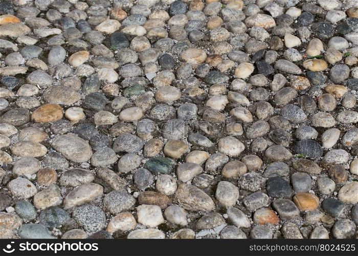 Round stones in the ground. Texture of the cobblestones in Park. Paved road for pedestrians. The paving stones. Background