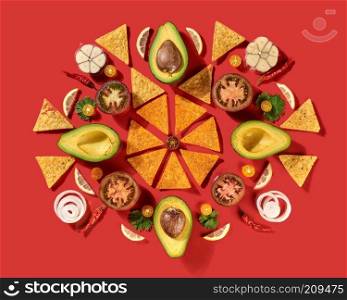 Round traditional mexican pattern with corn nachos chips, fresh natural fruits, vegetables, spices, chilli greens - ingredients for Guacamole dressing on a red background. Flat lay.. Mexican corn nachos chips, avocado, lemon, garlic, tomato, onion, parsley green as a round pattern - ingredients for tomato chili sauce on a red background. Top view.