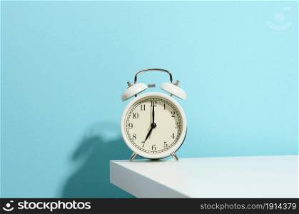 round white alarm clock on the table. Time seven in the morning, get up early, change hours