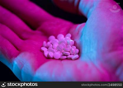 Round white drug pills tablets heap in hand on black background