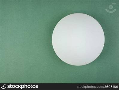 round white lamp on the green wall
