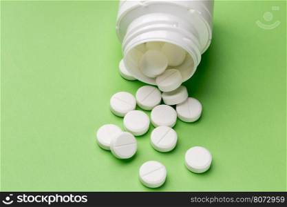 Round white pills and plastic pill bottle. Heap of round white tablets and plastic pills bottle