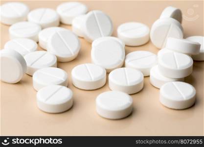 Round white pills. Heap of round white pills on beige background