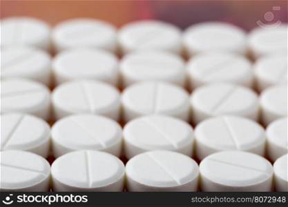 Round white pills. Heap of round white pills on colorful background