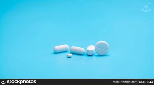 Round white tablets pills on blue background. Tablets and caplets pills pharmaceutical dosage form. Pharmacy and health topics background. Pharmaceutical industry banner. Online pharmacy store banner.
