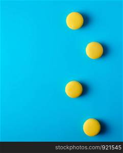 round yellow baked macaroons with cream lie on a blue background, top view